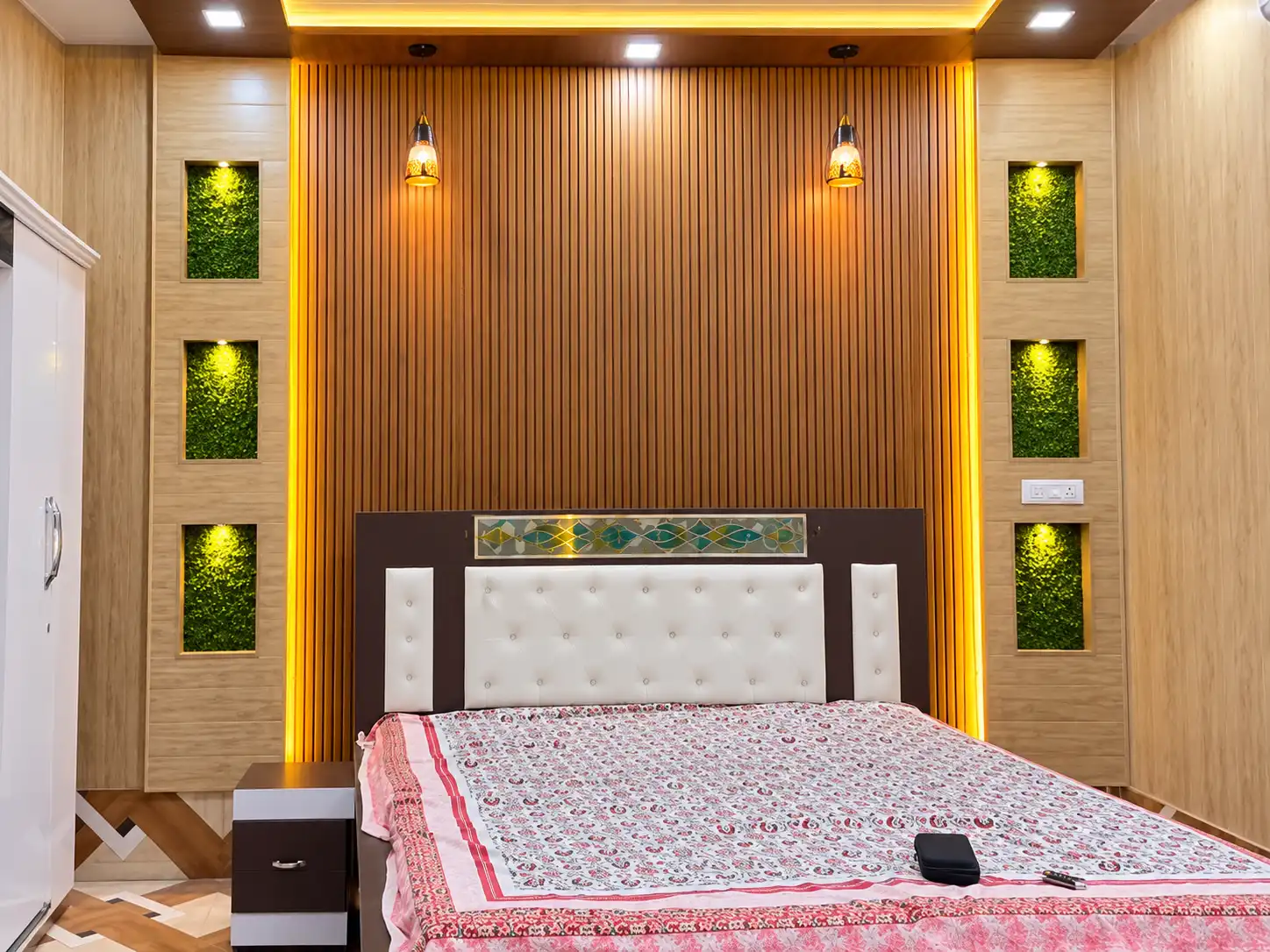 Warm wood fluted bedroom wall with a padded headboard and illuminated side niches