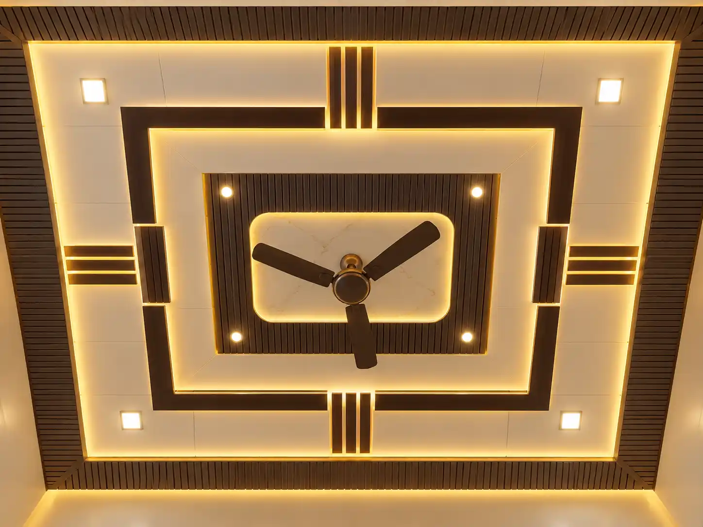 Layered PVC ceiling with warm lighting and a central ceiling fan